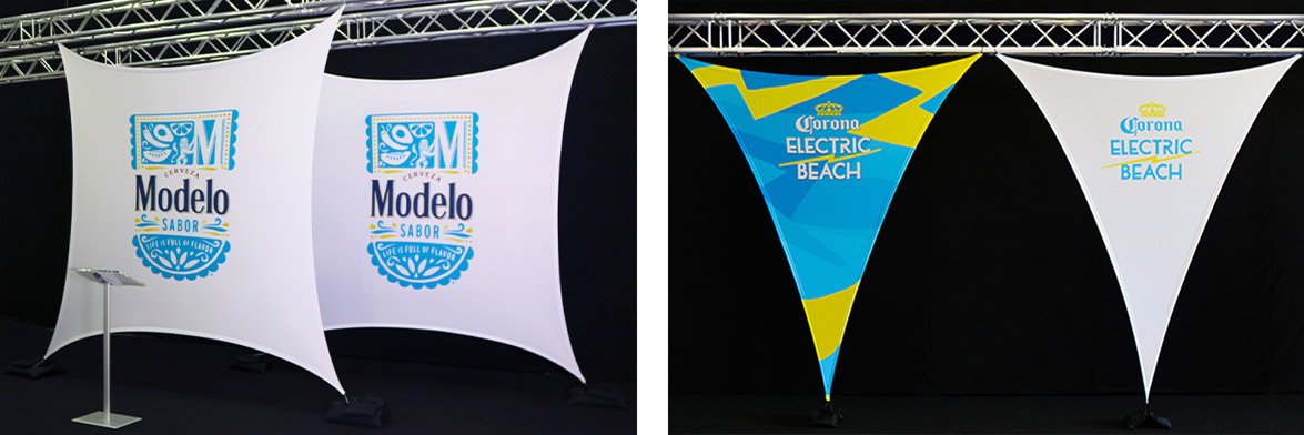 A pair of triangular printed flat panel sails, one blue and one white, with the Corona Electric Beach logo and two Square Stretch Triangles with the Modelo Beer Logo