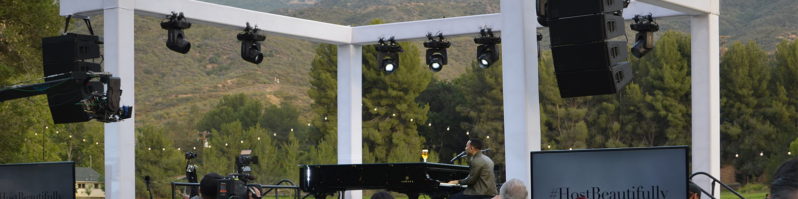 Man Playing Piano On Stage Surrounded By Light Blocking Truss Covers