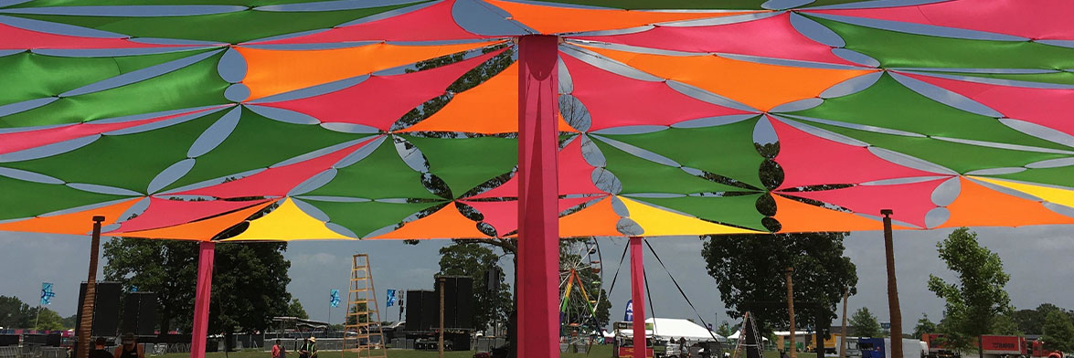 Yellow, Red, Green, And Orange Triangle Stretch Fabric Sails Connected To Make A Shade Structure